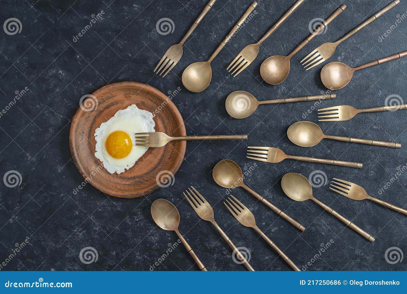керамическая тарелка с жареным яйцом и латунной вилкой и ложками .