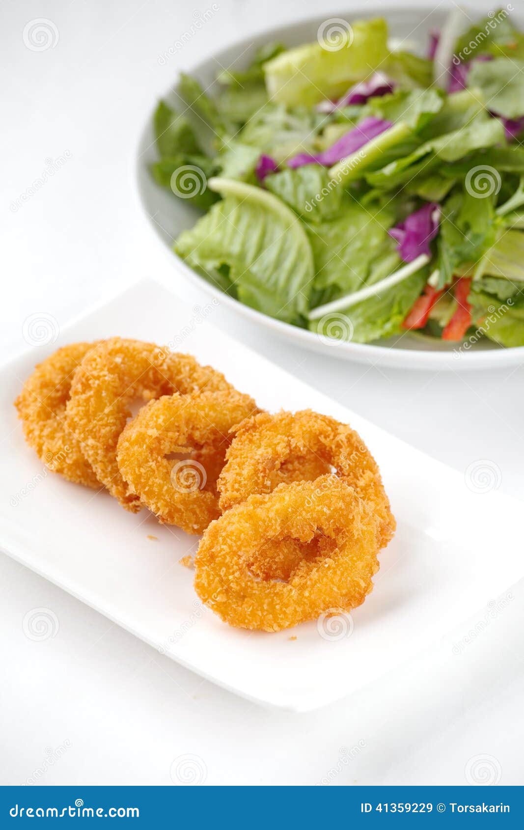 кольца зажаренные calamari. Глубокие зажаренные кольца calamari и зеленый салат овощей