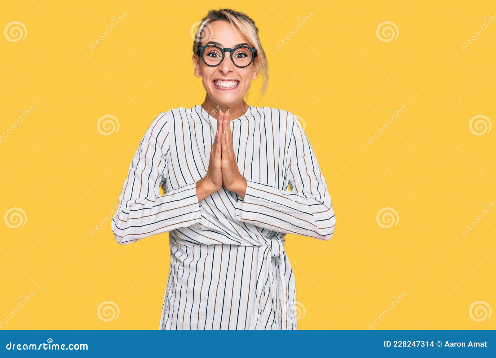 красивая блондинка в деловой рубашке и очках молится руками вместе ...