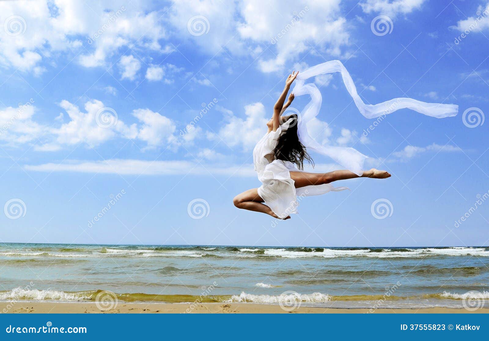 Красивая девушка скача на пляж. Красивая девушка при белый шарф скача на пляж