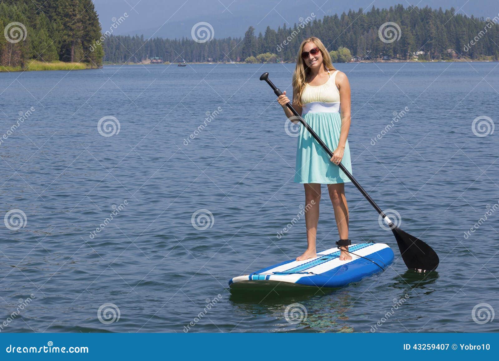Красивая женщина paddleboarding на сценарном озере. 3 милых дет наслаждаясь их летними каникулами совместно на озере