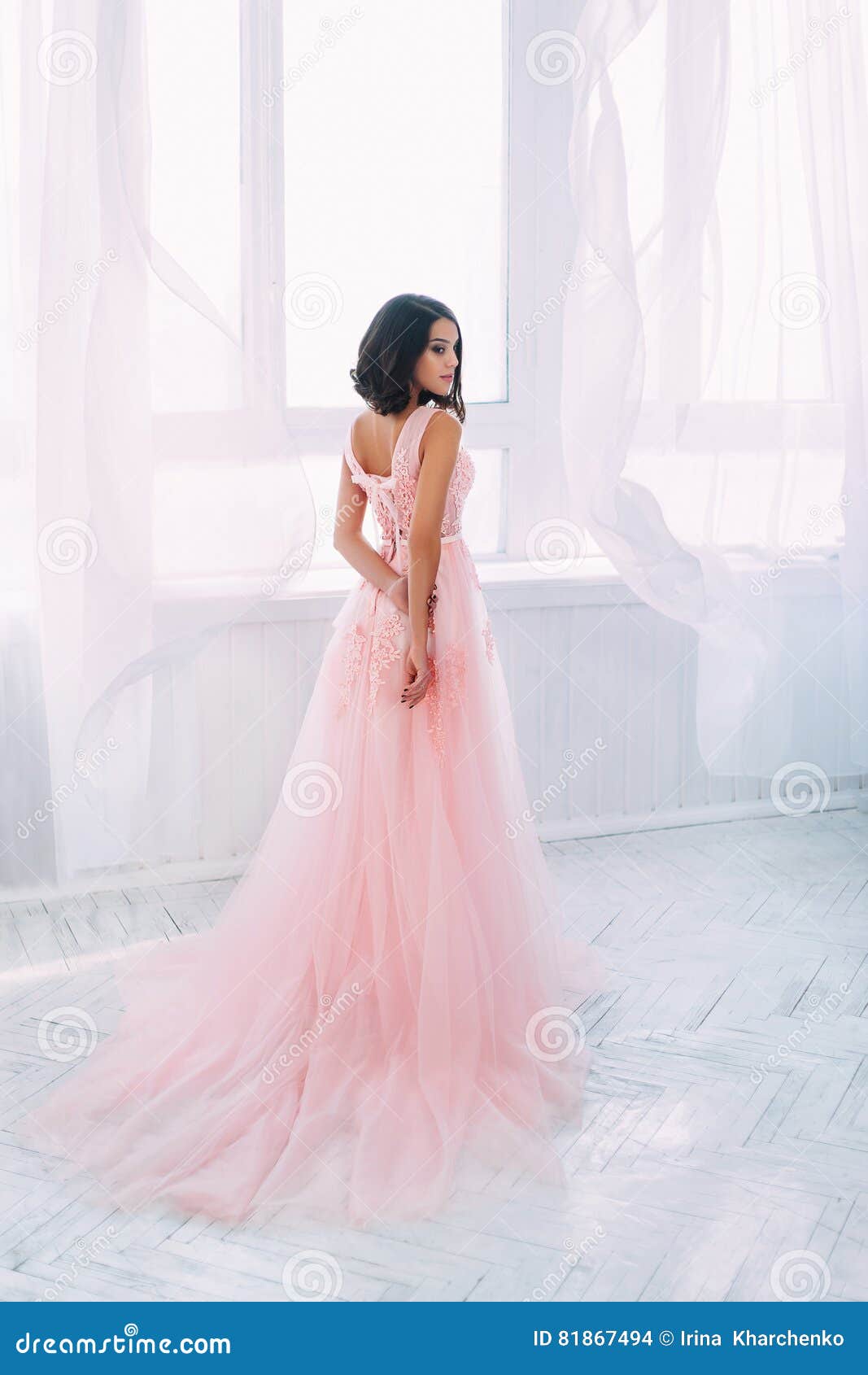 Красивейшая девушка брюнет. Красивая девушка брюнет стоя в светлой комнате Она одета в роскошном, пушистом, розовом платье Нежная сторона ` s марионетки Европейское изображение невесты Стиль светлого тонового изображения фото