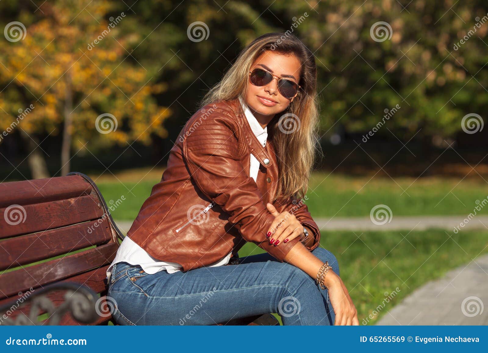 красивейшие белокурые детеныши женщины. Красивая молодая белокурая женщина сидя на стенде в парке