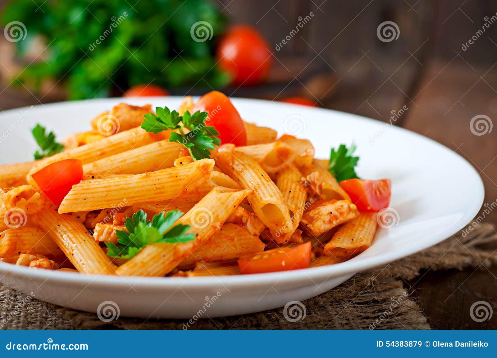 Макаронные изделия Penne в томатном соусе с цыпленком, томатами украшенными с петрушкой на деревянной предпосылке