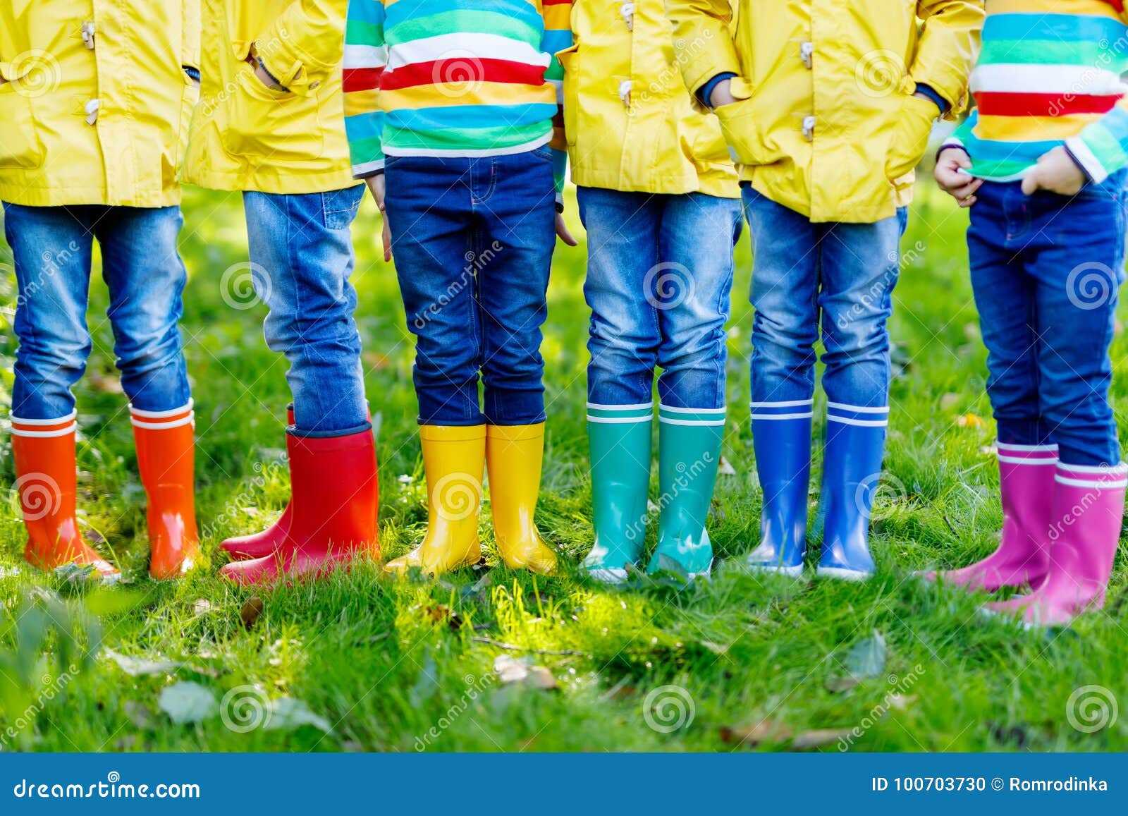 Маленькие ребеята, мальчики или девушки в джинсах и желтой куртке в красочных ботинках дождя Конец-вверх детей с различными резиновыми ботинками Обувь на ненастное падение Концепция яркой осени