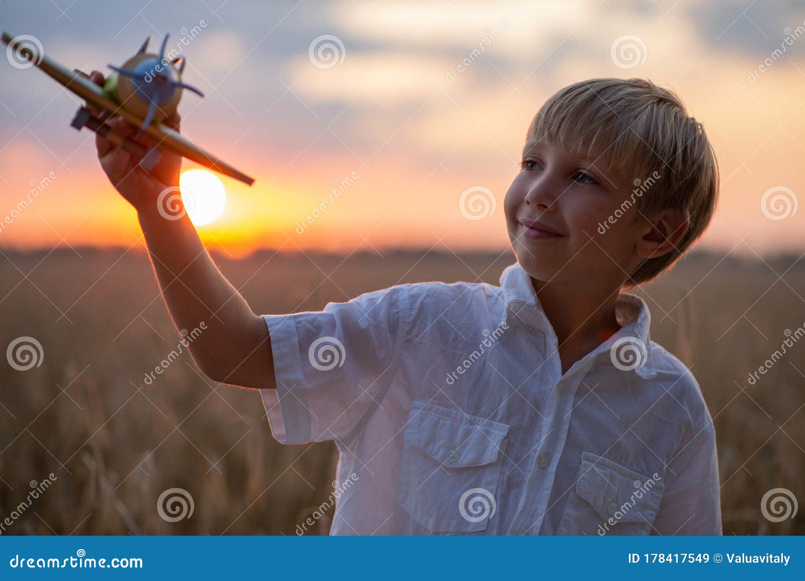 Мальчика в белой рубашке с самолетом в руках на фоне неба. Ребенок ...