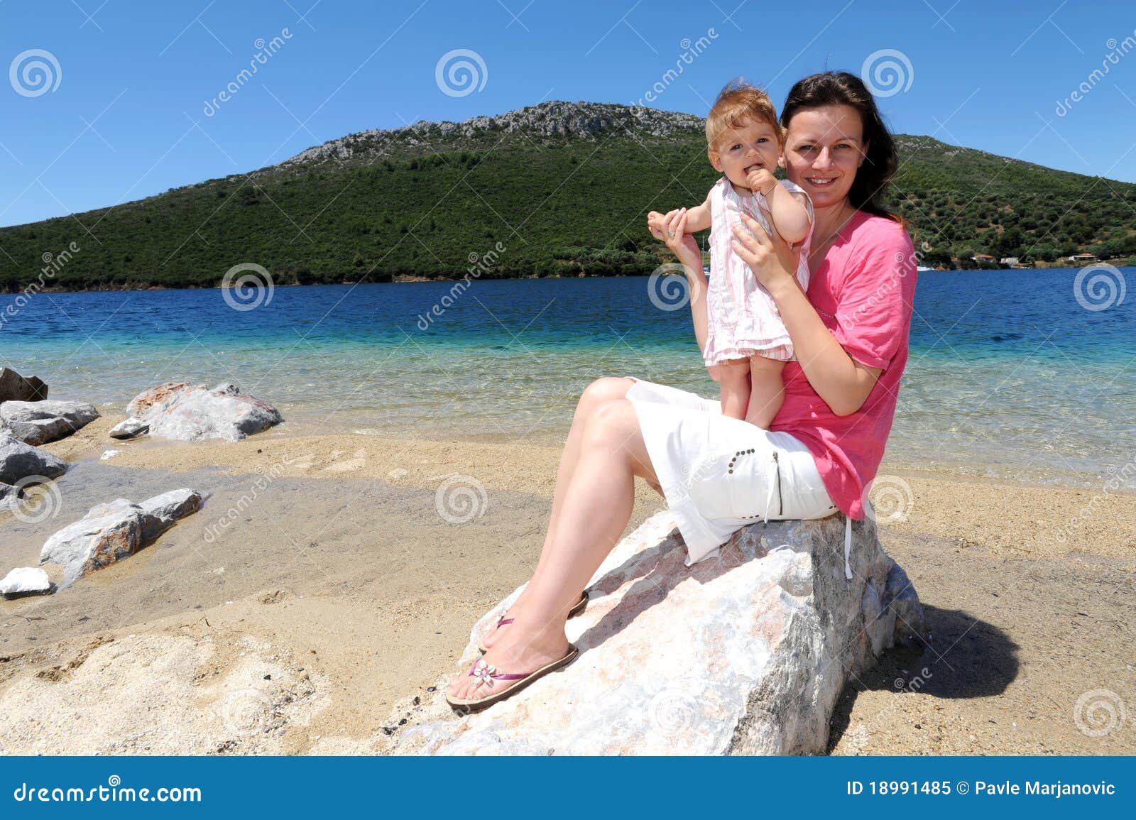 младенец приставает ее мать к берегу. пляж Греция младенца ее мать porto koufo