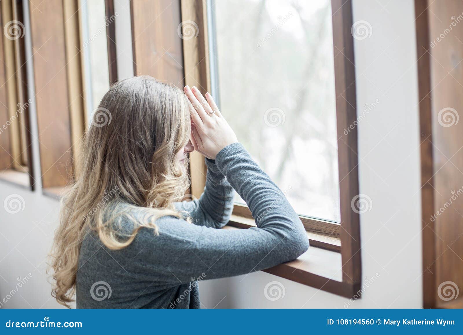 Молодая женщина моля окном. Молодая женщина вставать и моля в силле окна