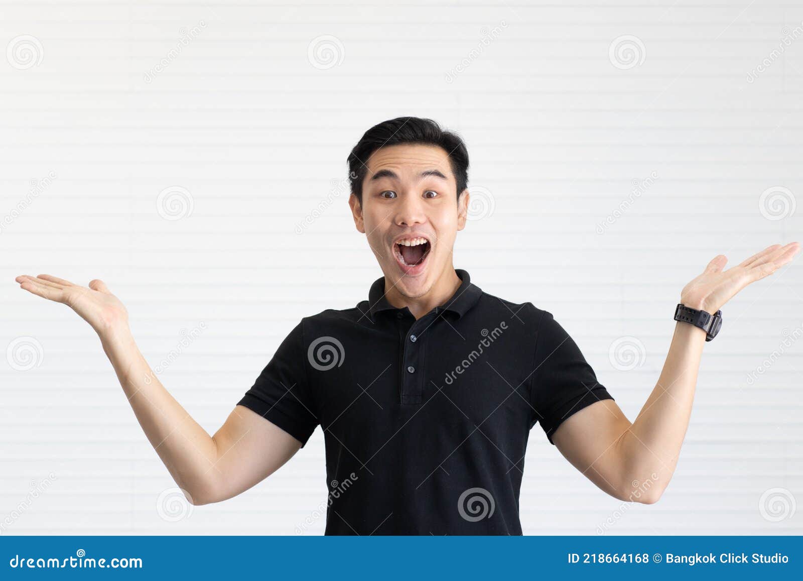 Возбужденный азиат в черной рубашке улыбается, держа телефон на белом фоне