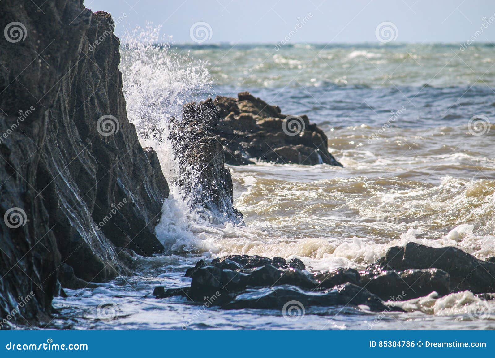 Море ударяя утесы. Море сталкиваясь против rockside в Уэльсе