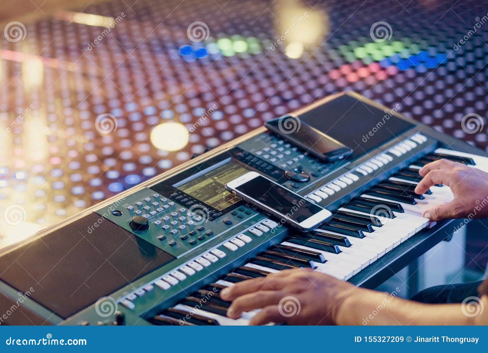 Музыкант сыграть электронные синтезаторы клавиатуры путем использование смартфона как директивы для игры на этапе концерта r. Музыкант сыграть электронные синтезаторы клавиатуры путем использование смартфона как директивы для игры на этапе концерта Выборочный фокус на смартфоне