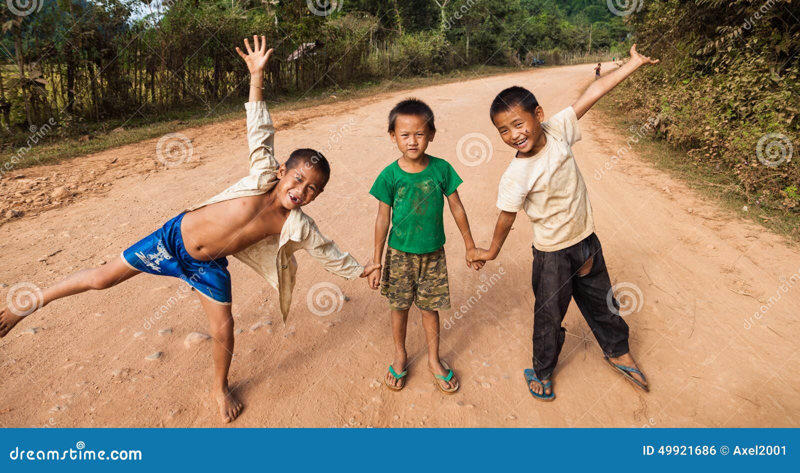 VANG VIENG, ЛАОС - 9-ОЕ НОЯБРЯ 2013: Неопознанные дети представляя на дороге в Vang Vieng, Лаосе 9-ого ноября 2013 Vang Vieng ориентированный на туризм городок в Лаосе популярном среди молодых иностранных туристов