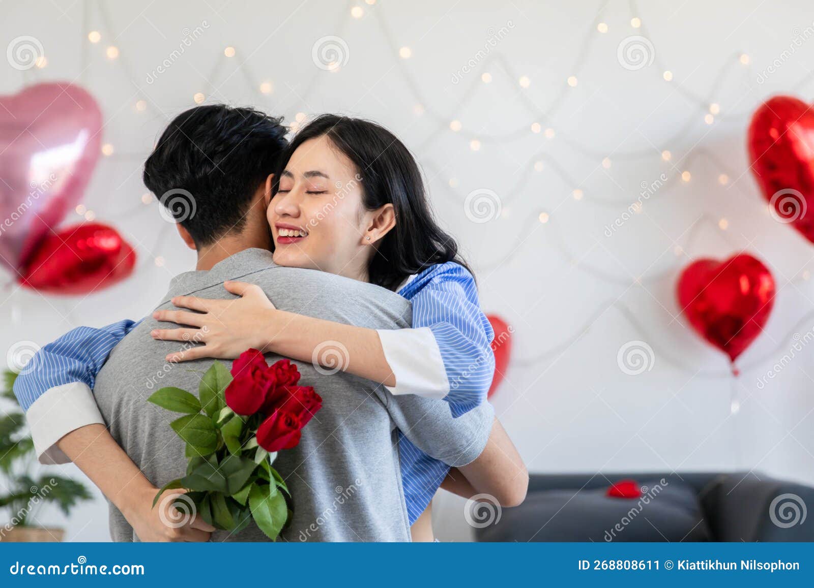 пара влюблена в обнимание в спальне с розами и подарочными подарками.