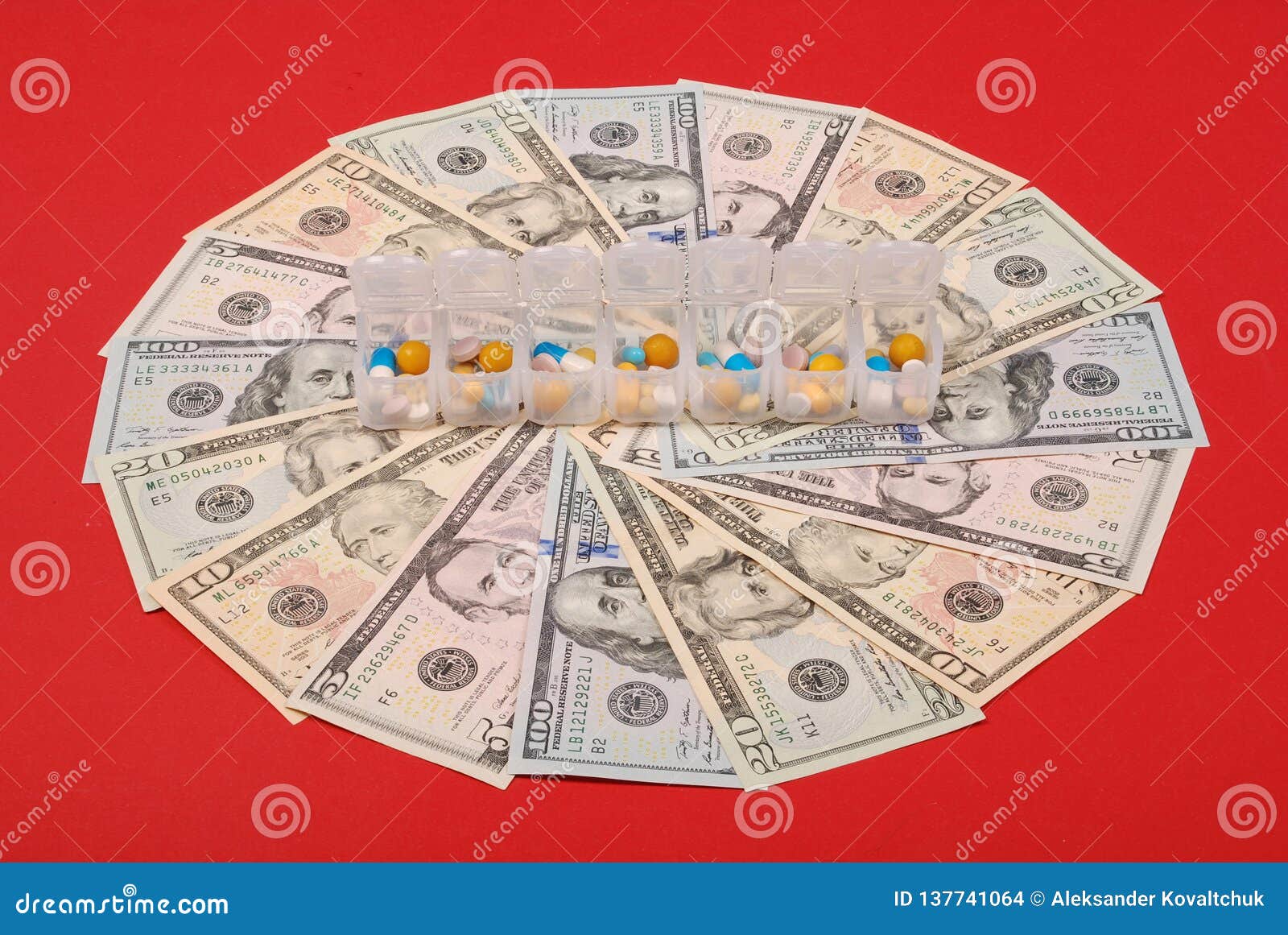 Покрашенные капсулы в открытой коробке на деньгах, в форме круга на красной предпосылке