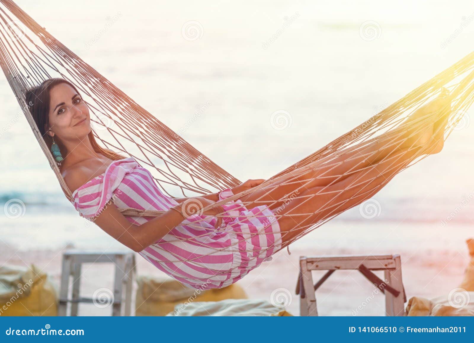 Портрет девушки в гамаке против моря на заходе солнца