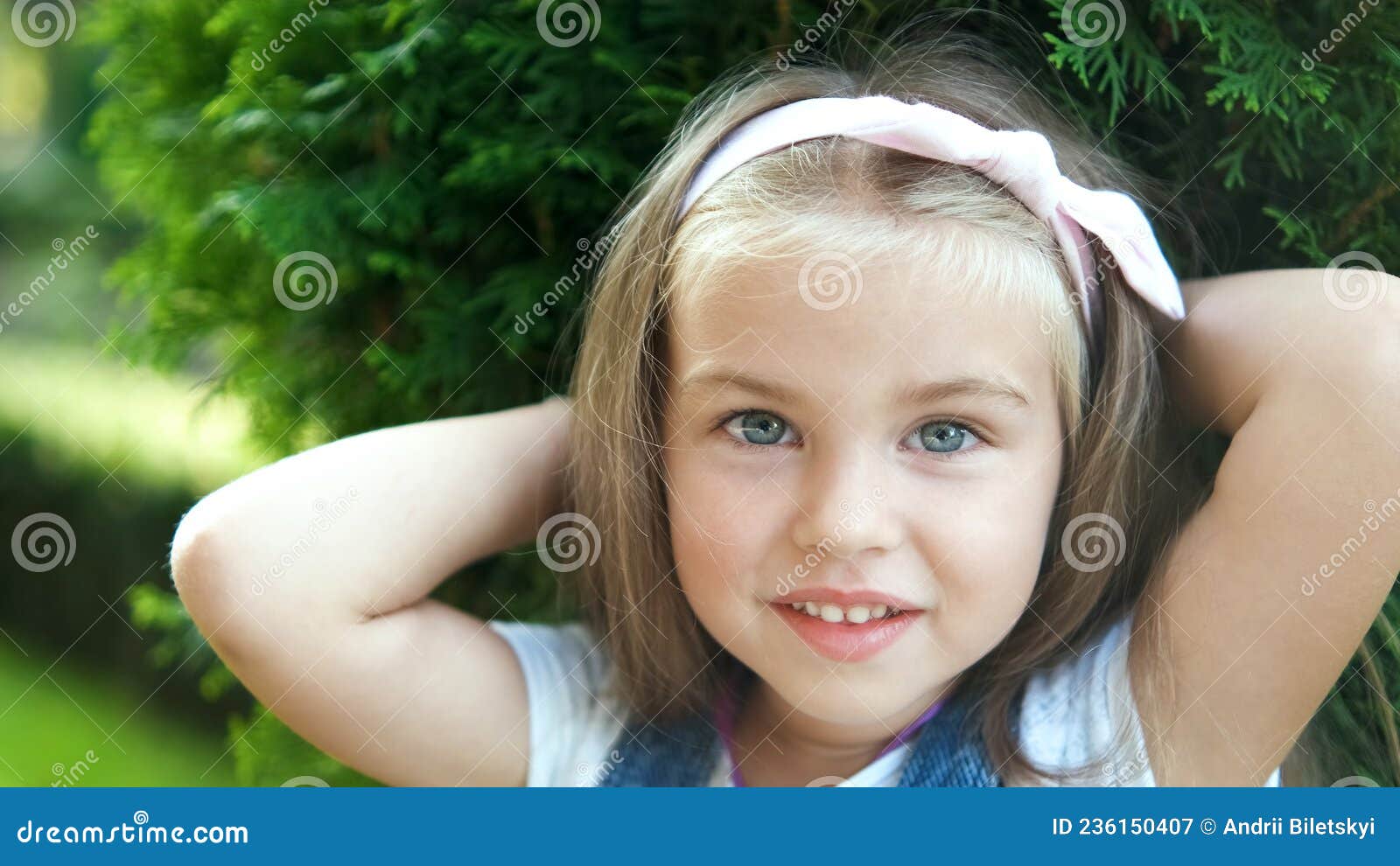 портрет счастливой красавицы девочки, стоящей в летнем парке, смотрящей ...