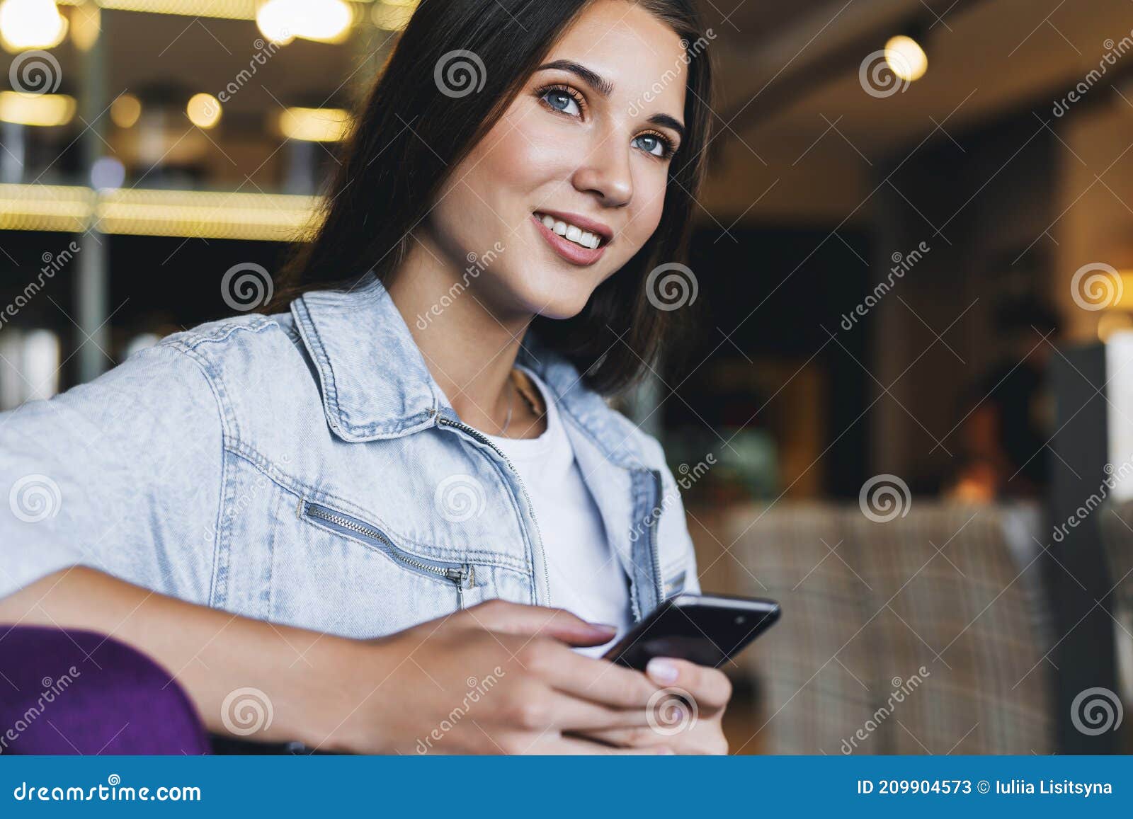 Привлекательная бизнес-леди сидит на столе перед ноутбуком и переговоры ...