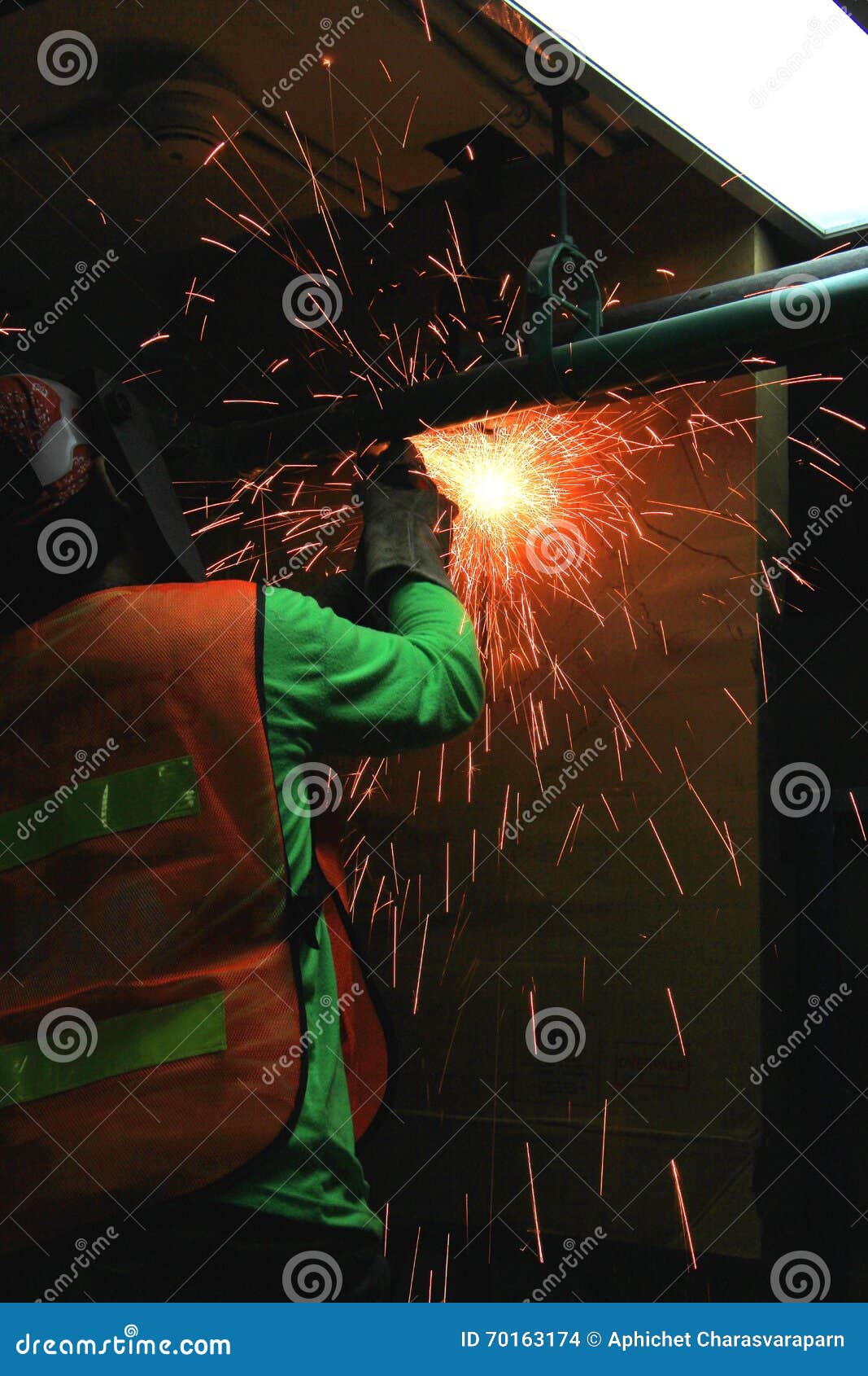 Работник режа старую стальную трубу. Вырезывание работника старой стальной трубы с брызгает искр