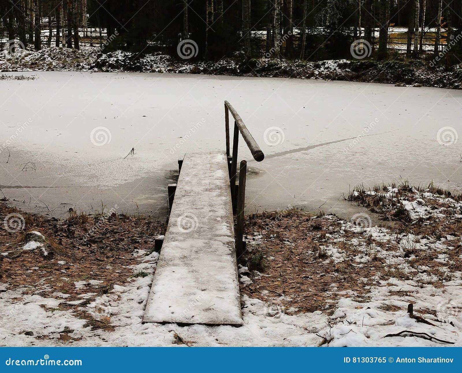 Россия - Архангельск - зимний день на пригороде Forest Park -, который замерли пруде и старом сломанном деревянном мосте с handho