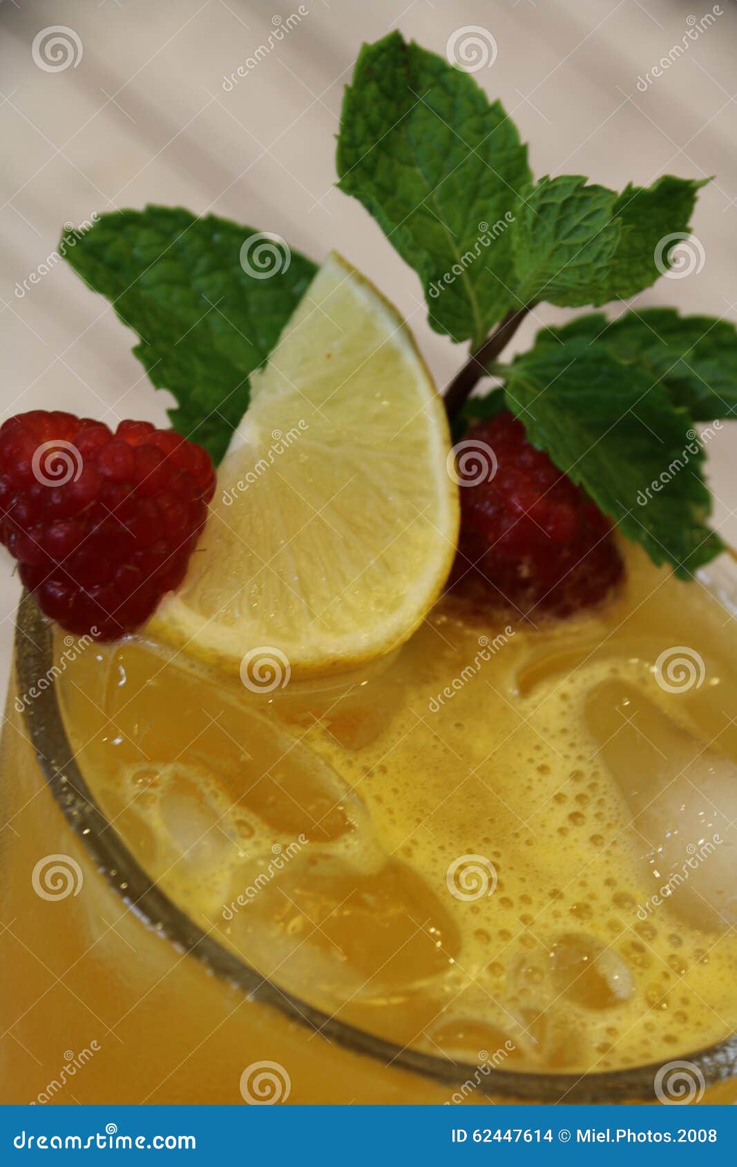 Свежий замороженный апельсиновый сок. Свеже сжиманный апельсиновый сок в стекле заполненном с кубами льда и гарнированном с лимоном, полениками, листьями мяты