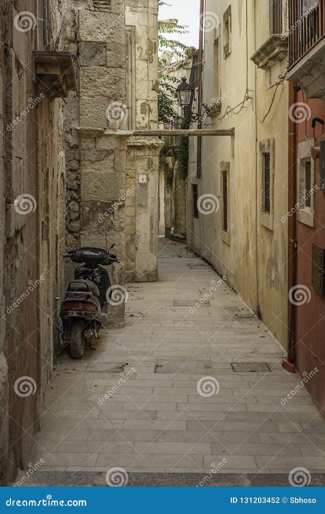 Старый мопед припаркованный в дезертировать и узкой улочке в старом городском историческом районе Ortigia, Сицилии