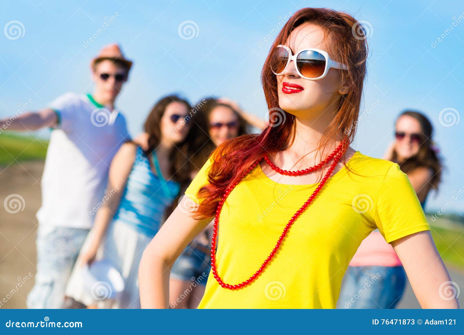 Стильная молодая женщина в солнечных очках. Стильные молодые женщины в солнечных очках на предпосылке голубого неба и друзей