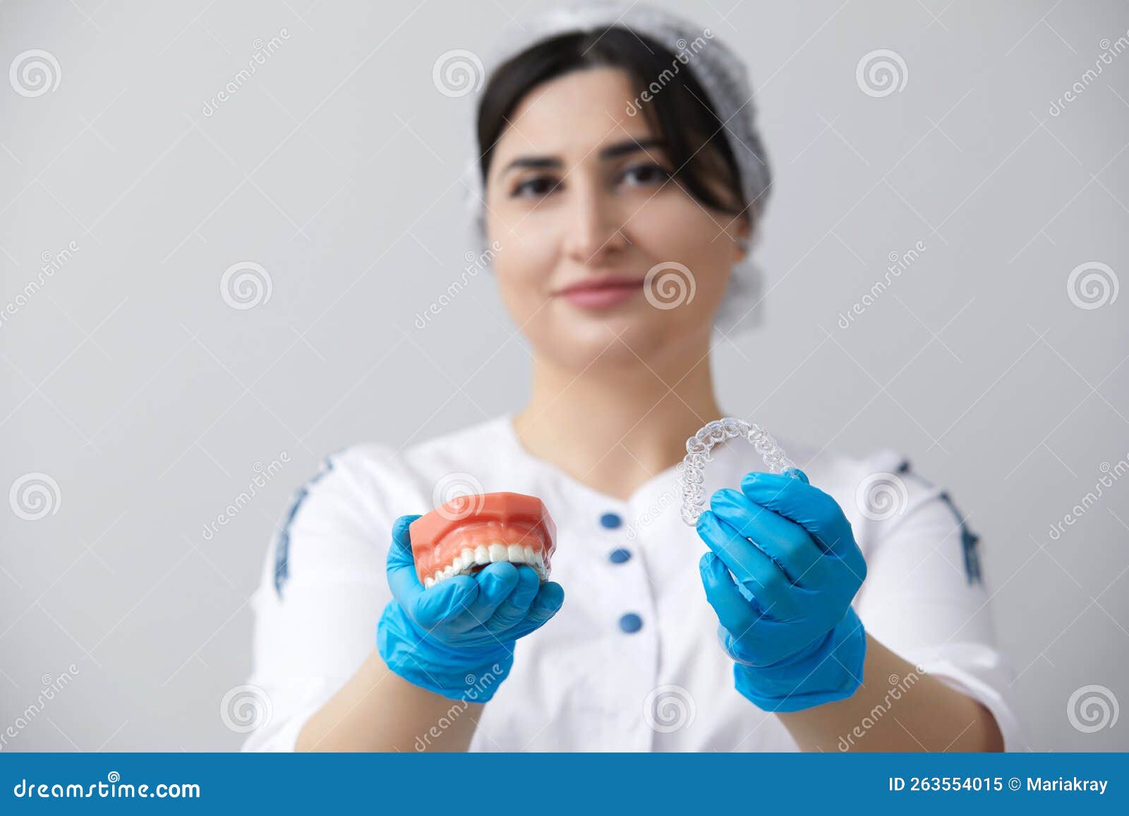 стоматолог показывает модель челюсти человека с проводными брекетами и ...