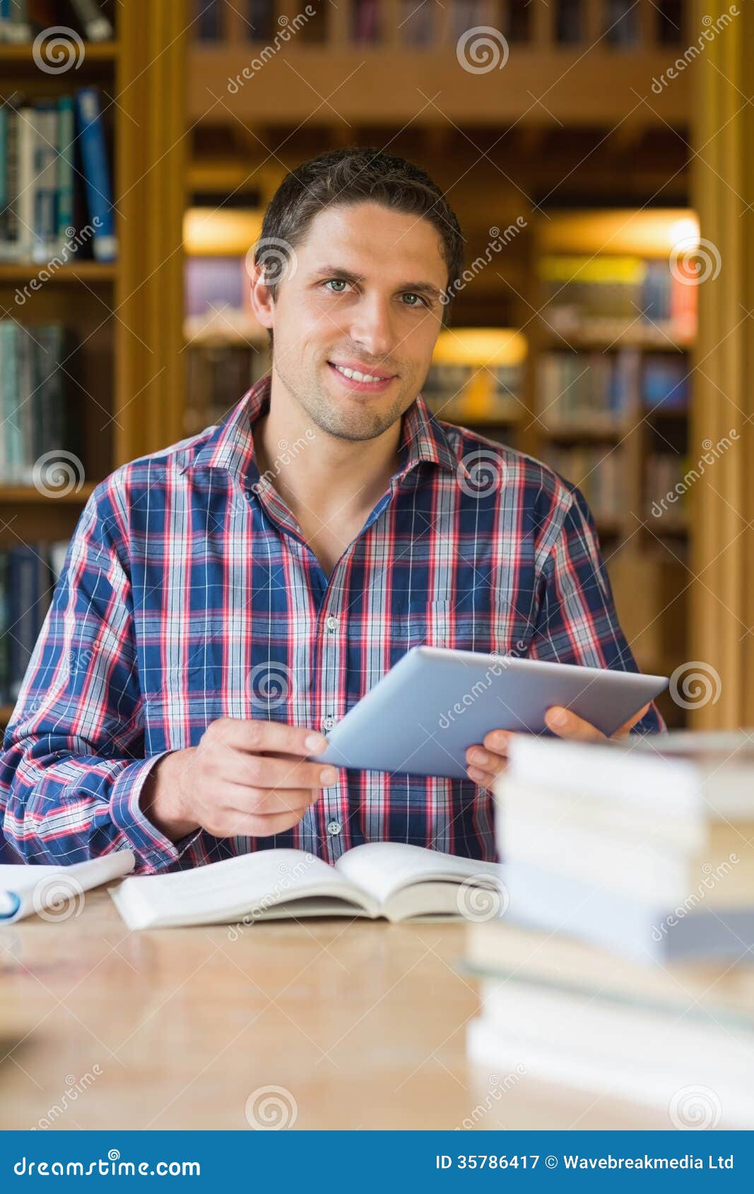 Счастливый зрелый студент держа ПК таблетки в библиотеке Стоковое ...