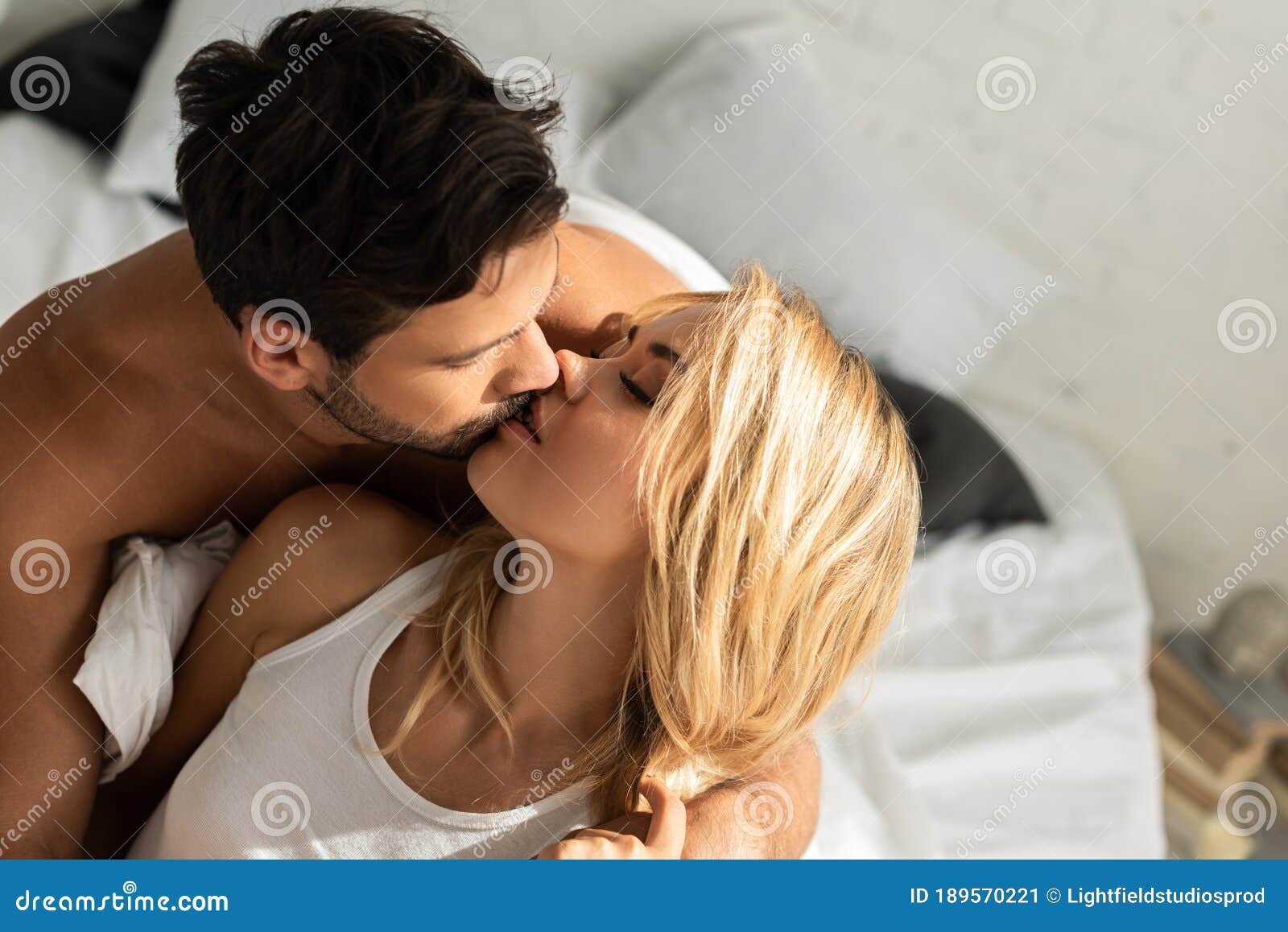 Пара целуется в постели Фото