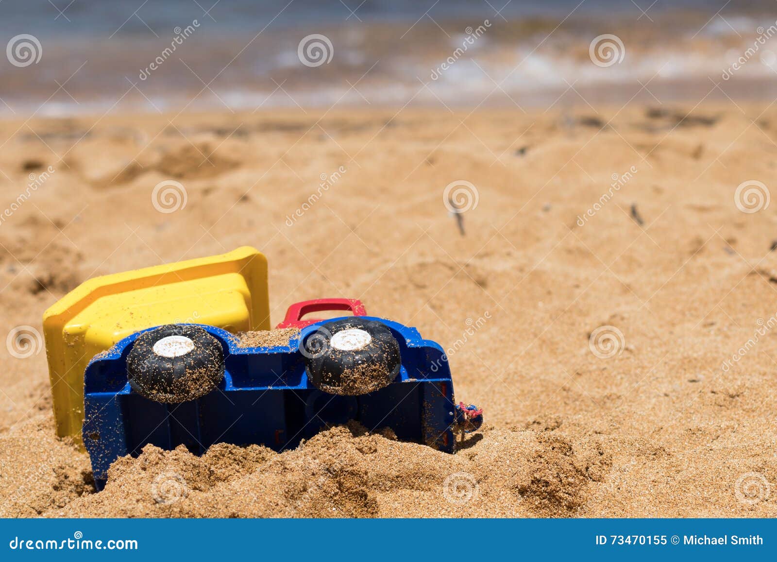 Тележка игрушки Sandy пластичная на среднеземноморском пляже. Потеха пляжа праздника, тележка игрушки на солнечном пляже