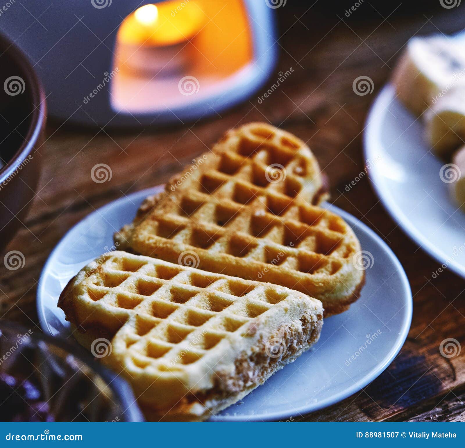2 торта вафли в форме сердца лежат на малой плите на, который служат деревянном столе Рядом с плитой отрезанных бананов, шара творога и фондю с шоколадом