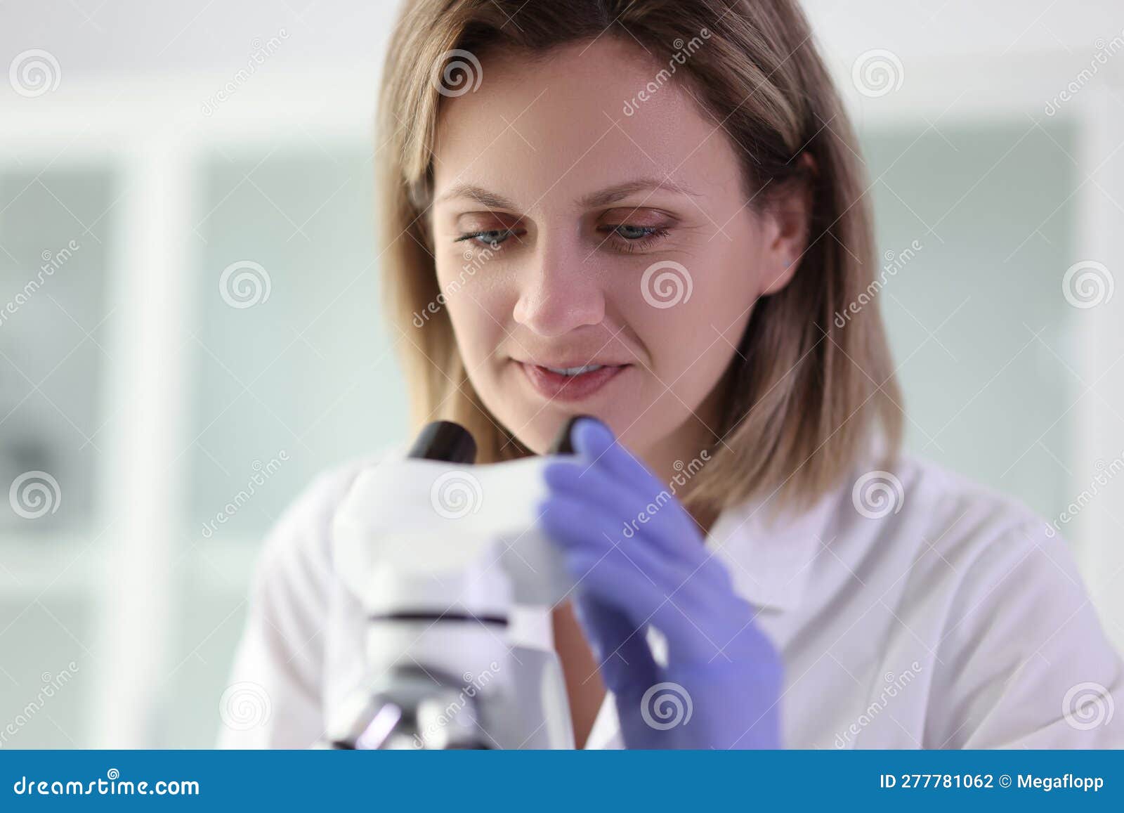 улыбающийся ученый смотрит в микроскоп на образец материала Стоковое ...