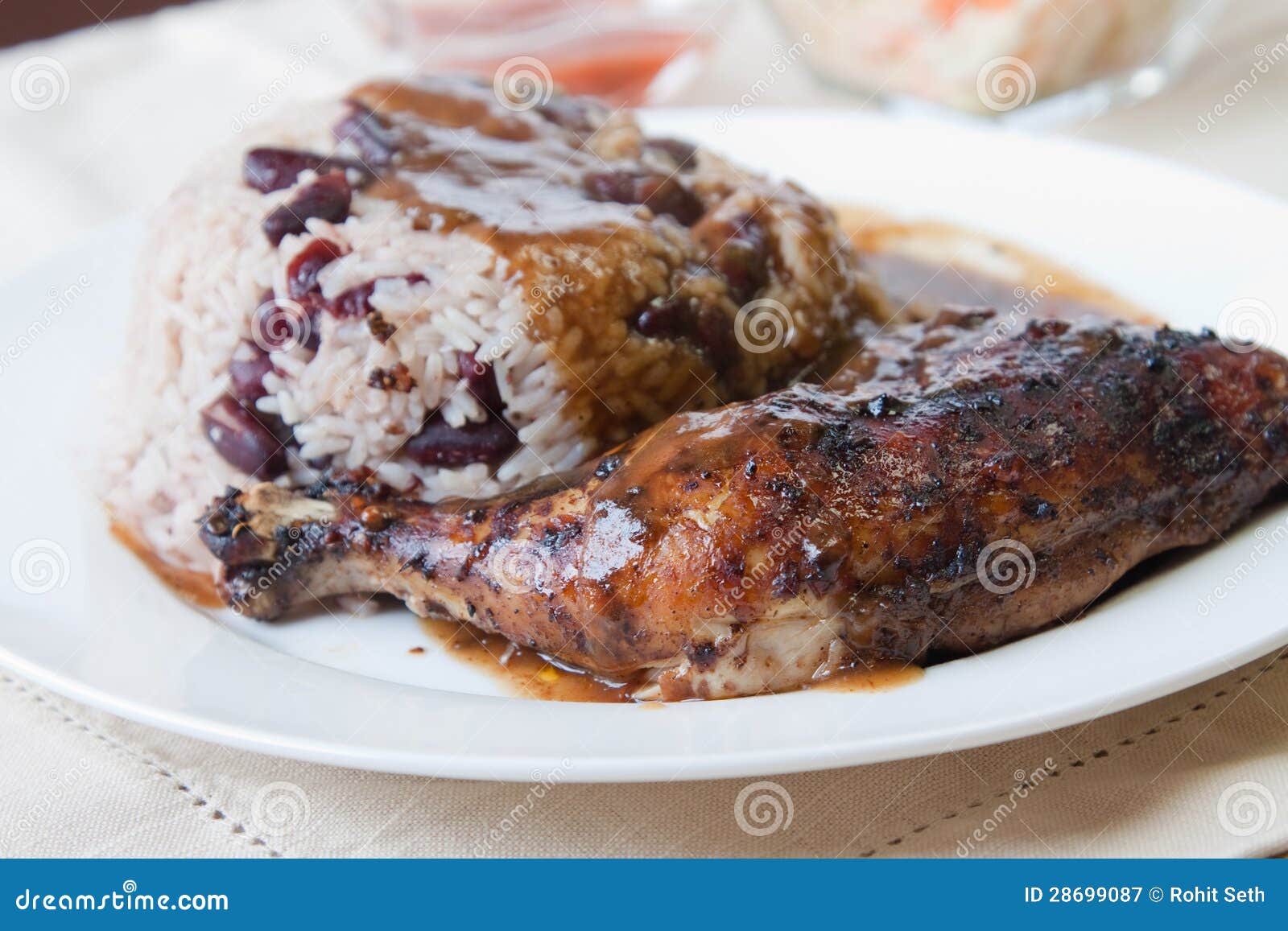 Цыпленок рывка с рисом - карибским типом. Карибский цыпленок рывка типа служил при рис смешанный с красными фасолями почки. Тарелка сопровоженная с coleslaw. Отмелый фокус на цыпленке.