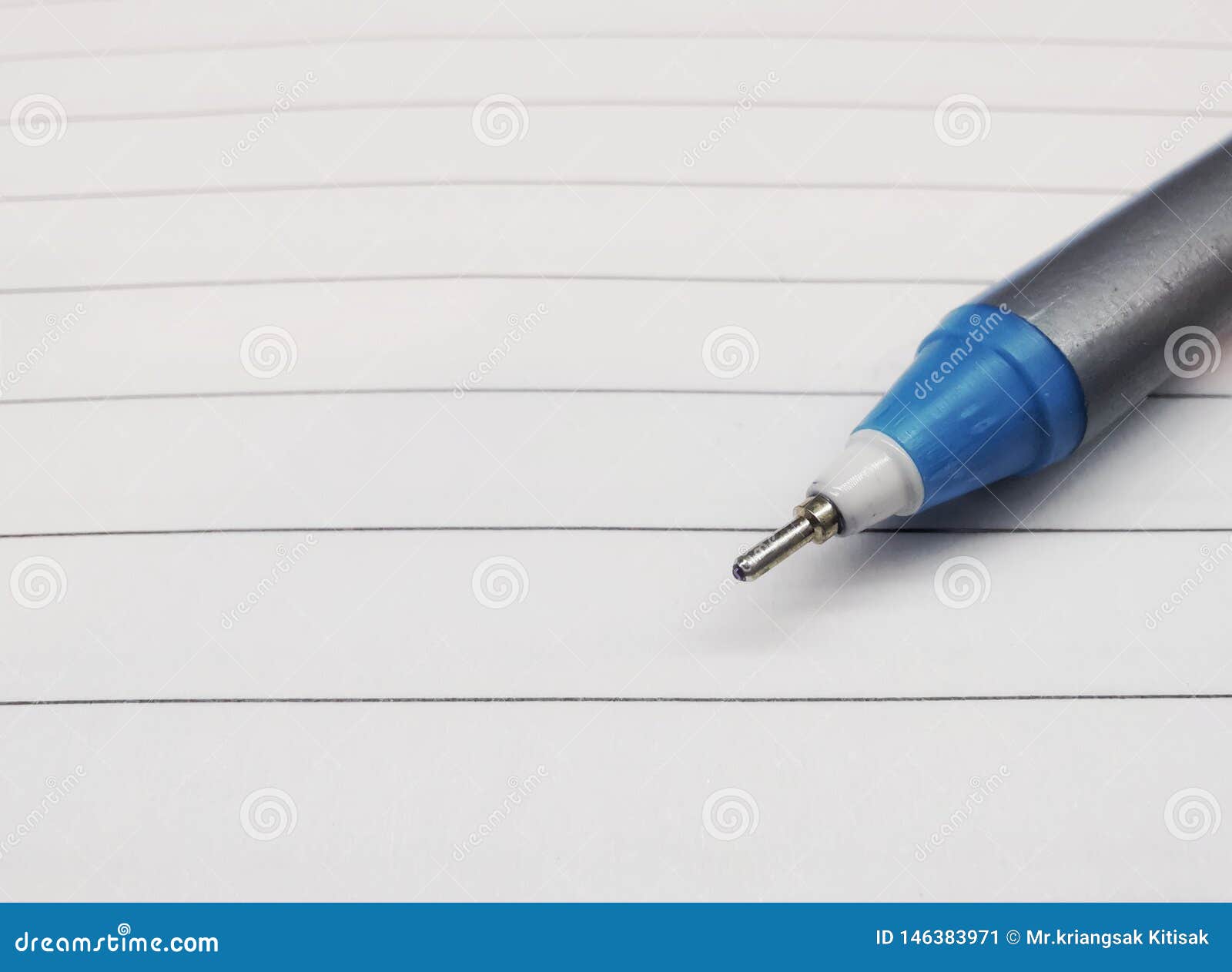 一只手拿着一支铅笔，准备在白色书桌上的粉红色便条纸上写字。照片摄影图片_ID:417928704-Veer图库