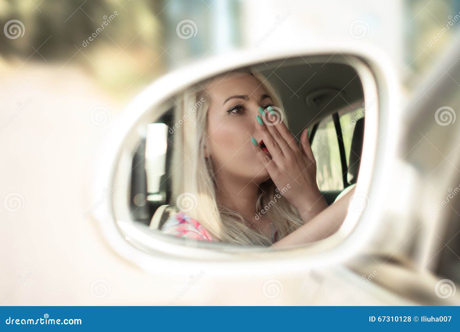 司机女孩哈欠，当驾驶汽车时. 司机女孩打呵欠，当驾驶在镜子时的一辆汽车