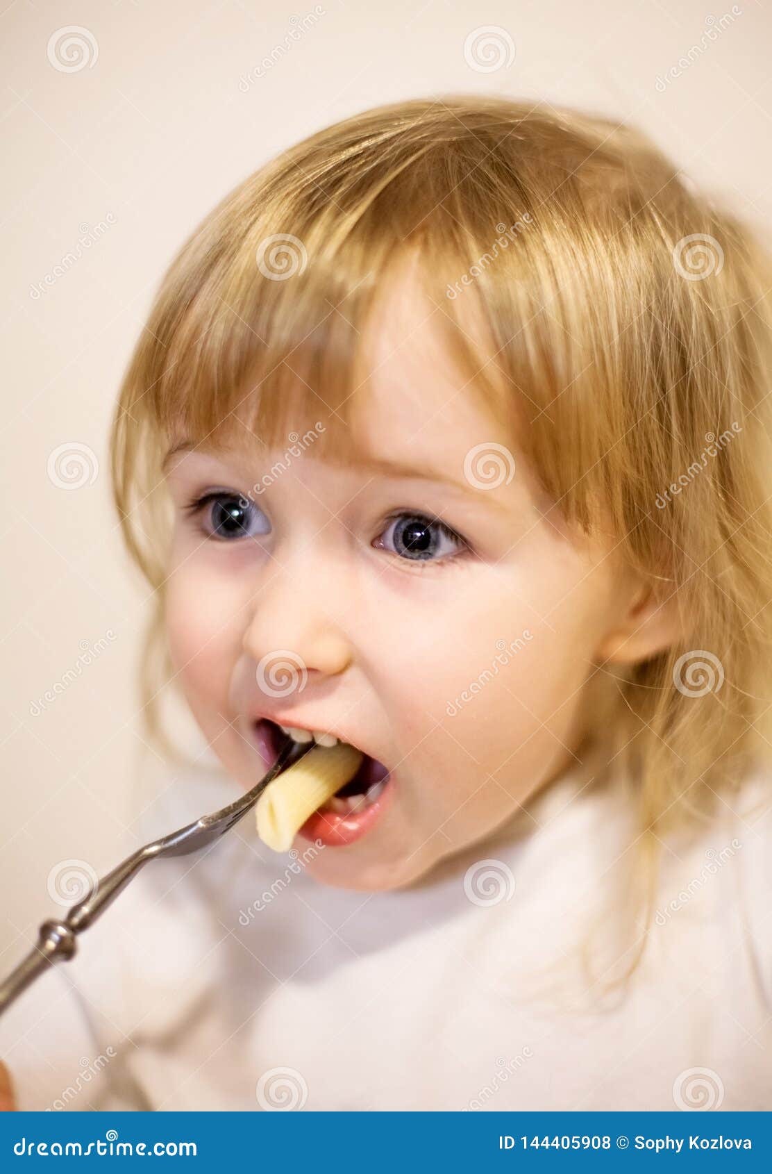 吃面团的女孩的特写镜头面孔由叉子. 吃面团的一点白女孩的特写镜头面孔由叉子
