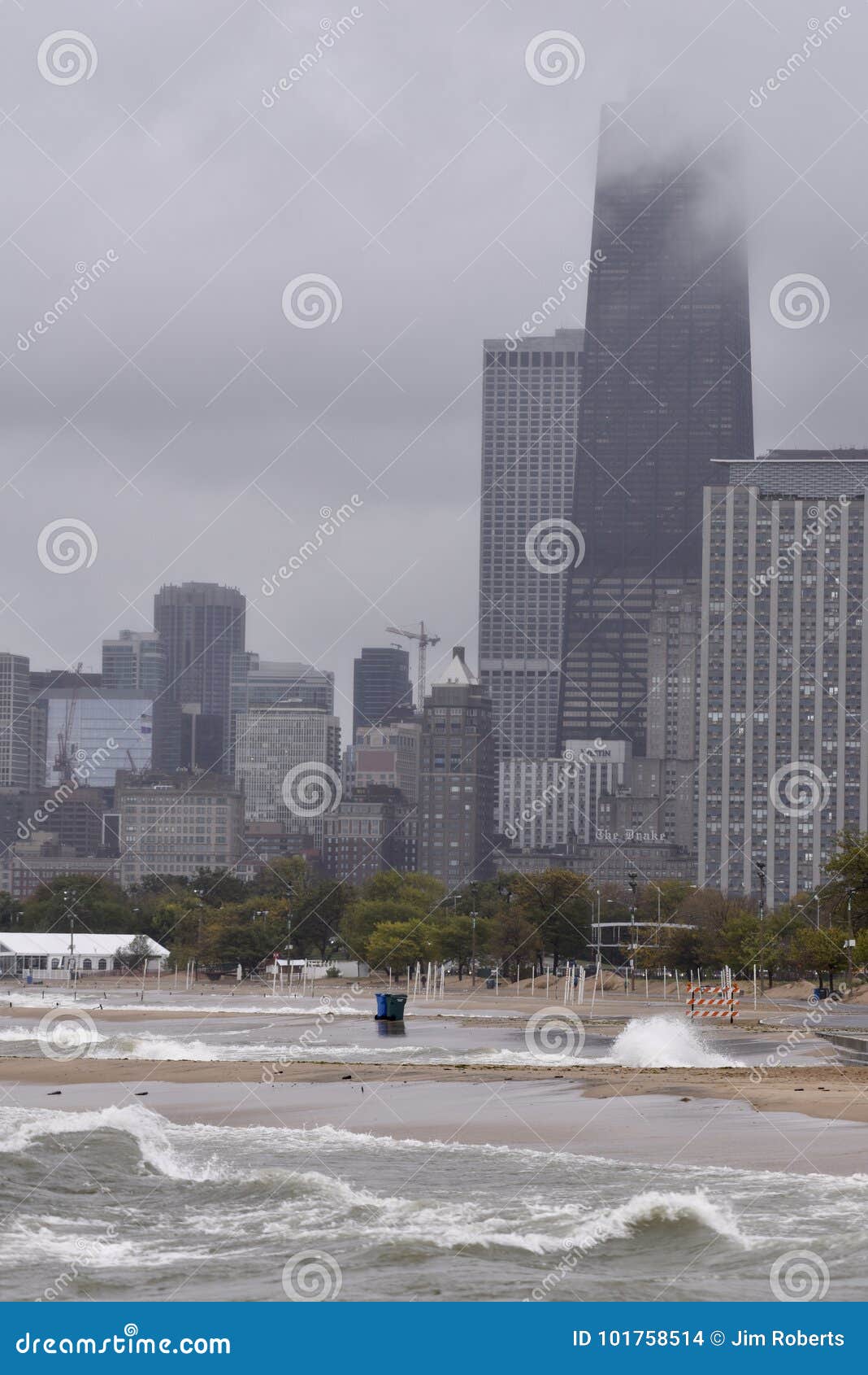 在橡木街道海滩的风雨如磐的早晨. 这是一个风雨如磐的早晨的秋天图片在橡木海滩芝加哥位于在密歇根湖的街道，伊利诺伊在库克县 这张图片以与偶象芝加哥地界的碰撞的海浪为特色在背景中包括在云彩和各种各样的旅馆覆盖的汉考克中心 这张照片拍了2017年10月11日