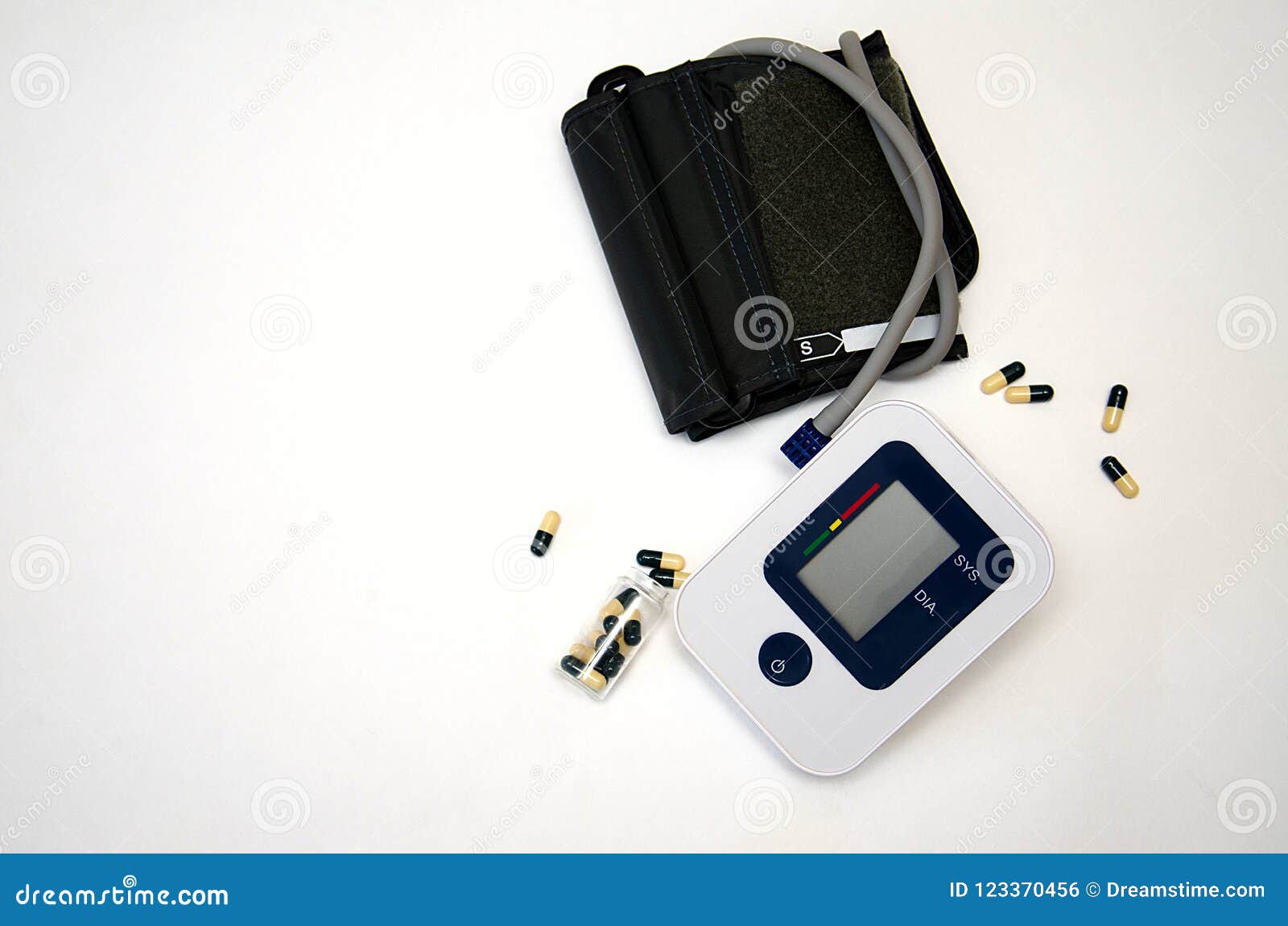 在白色背景的电子血压tonometer. 青白的电子tonometer、措施血压和脉冲，在谎言胶囊和药片黄色和蓝色旁边，在白色背景
