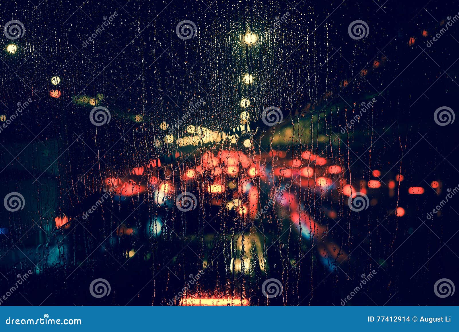 城市视图通过一个窗口在多雨夜，雨在与路光bokeh，城市生活的窗口在雨季摘要背景中下降在夜