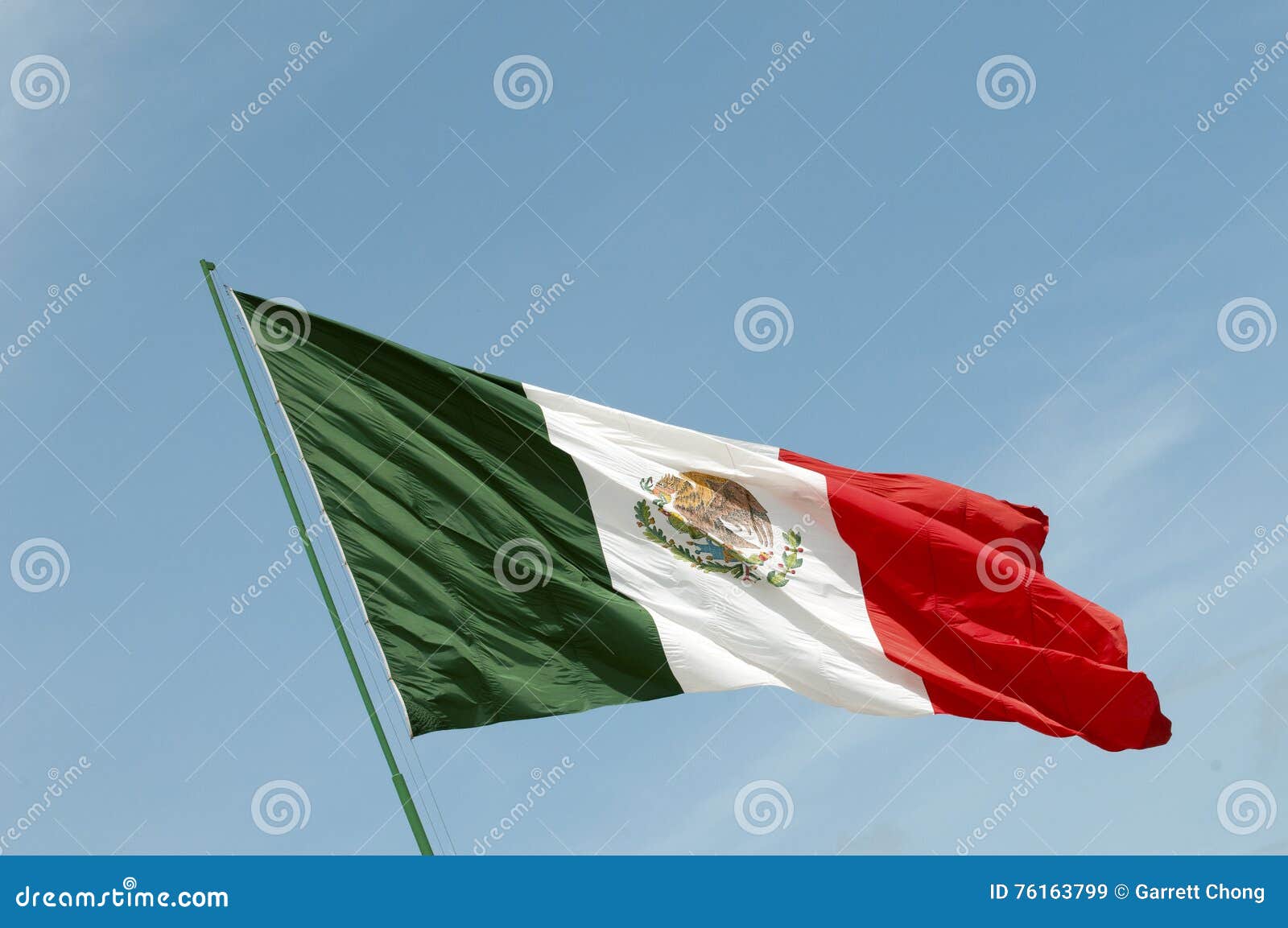 墨西哥全国沙文主义情绪反对蓝天. 在风的一个墨西哥国旗拍动反对蓝天背景