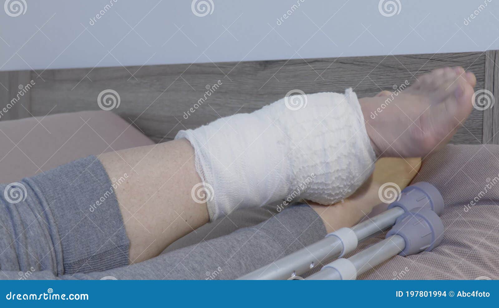一名戴着医用手套的医生在病人的腿和膝盖上缠绕着弹性绷带。高清摄影大图-千库网
