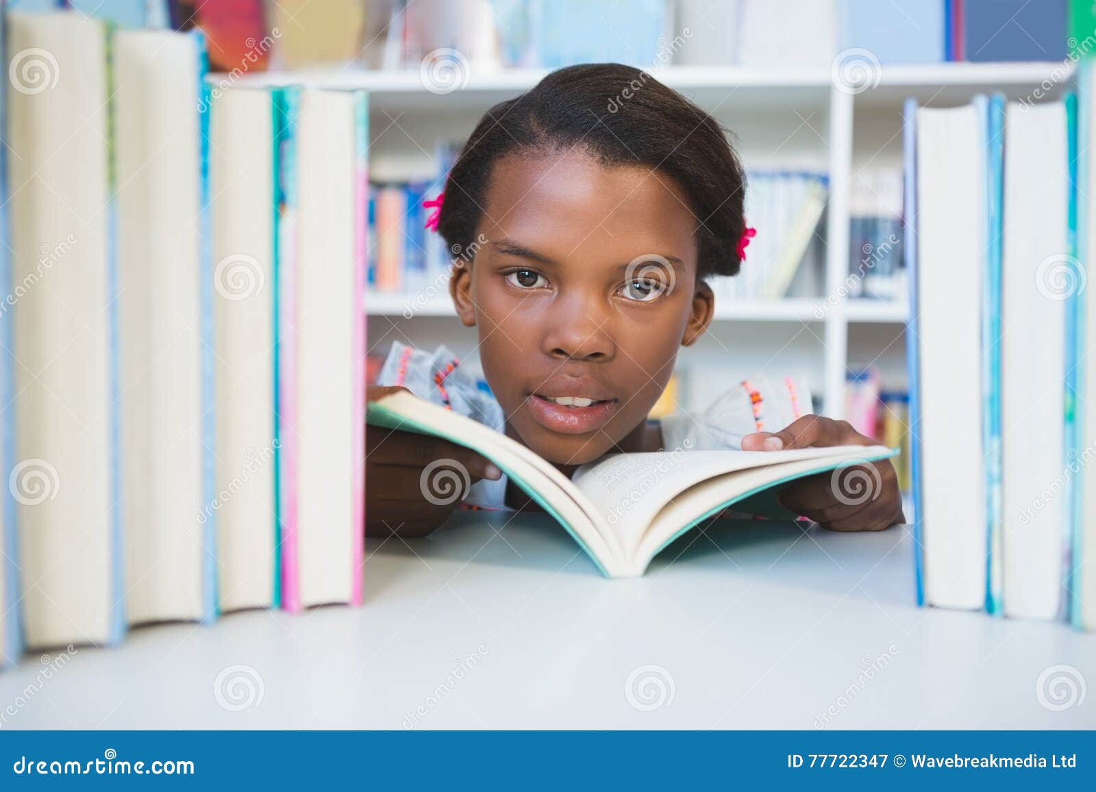 女小学生阅读书在图书馆里. 女小学生阅读书画象在图书馆里在学校