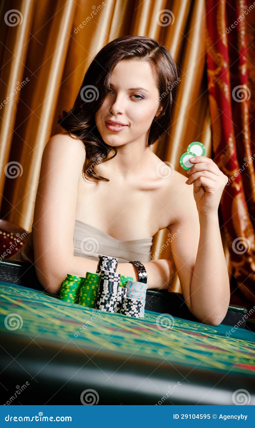 女性赌客在与筹码的使用的表. 在手中坐在与筹码的使用的表的女性赌客纵向