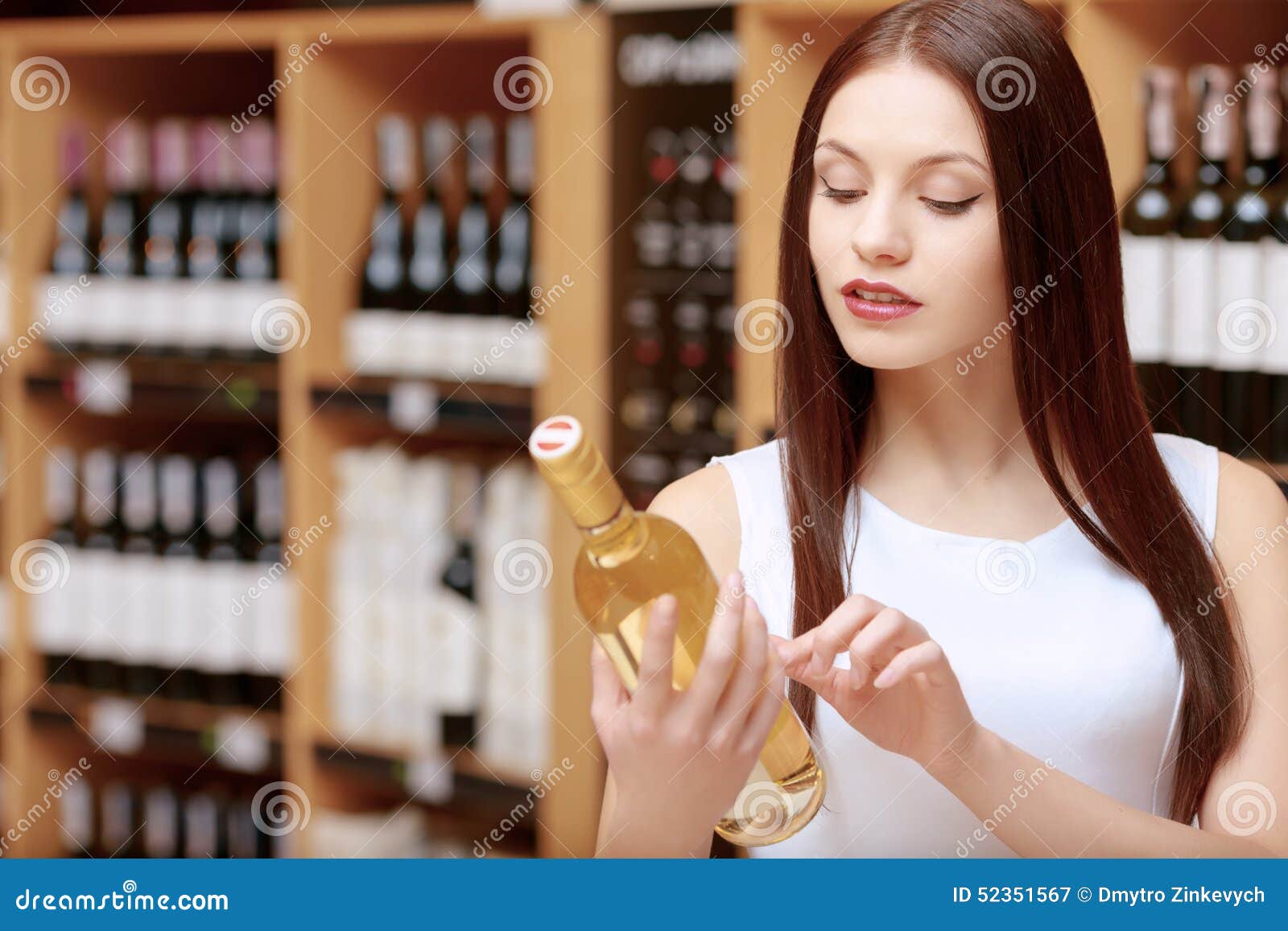两个性感的女人笑着拿着一个酒瓶和一个礼品盒在粉红色的背景照片摄影图片_ID:350806509-Veer图库