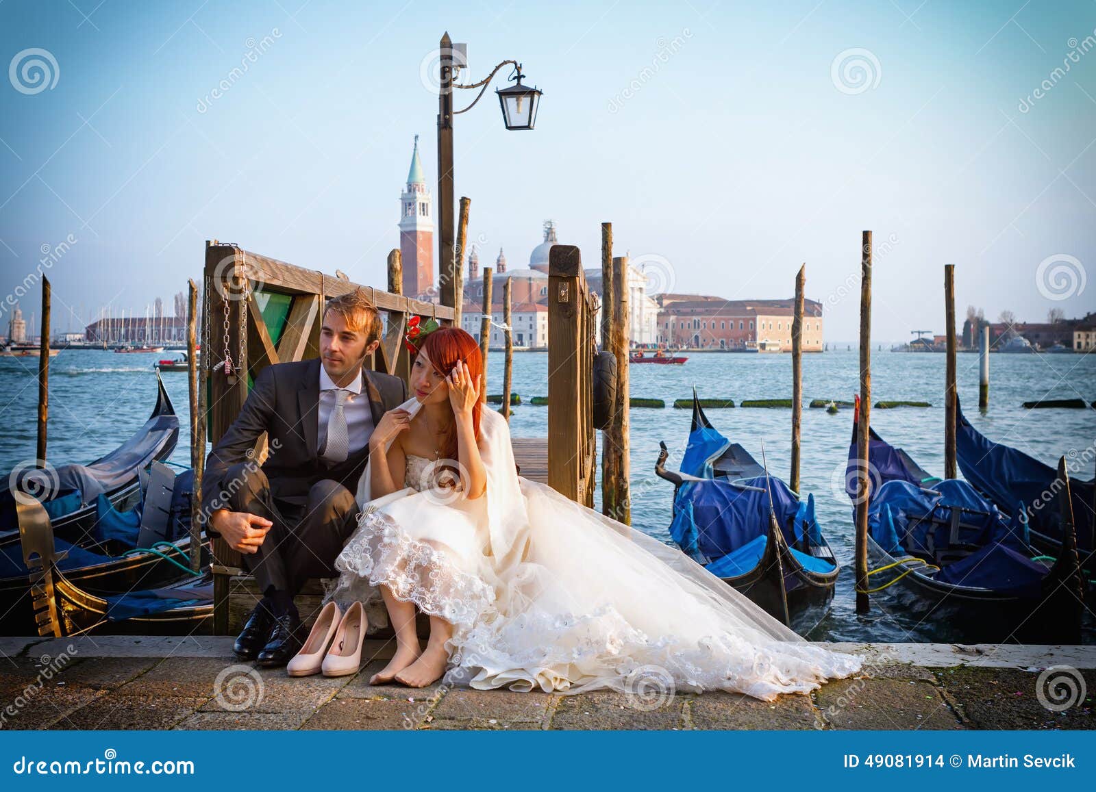 婚姻在日落的威尼斯. 威尼斯，意大利- 2014年2月27日：未认出的人，婚姻的夫妇坐一个码头在威尼斯， 2014年2月的意大利