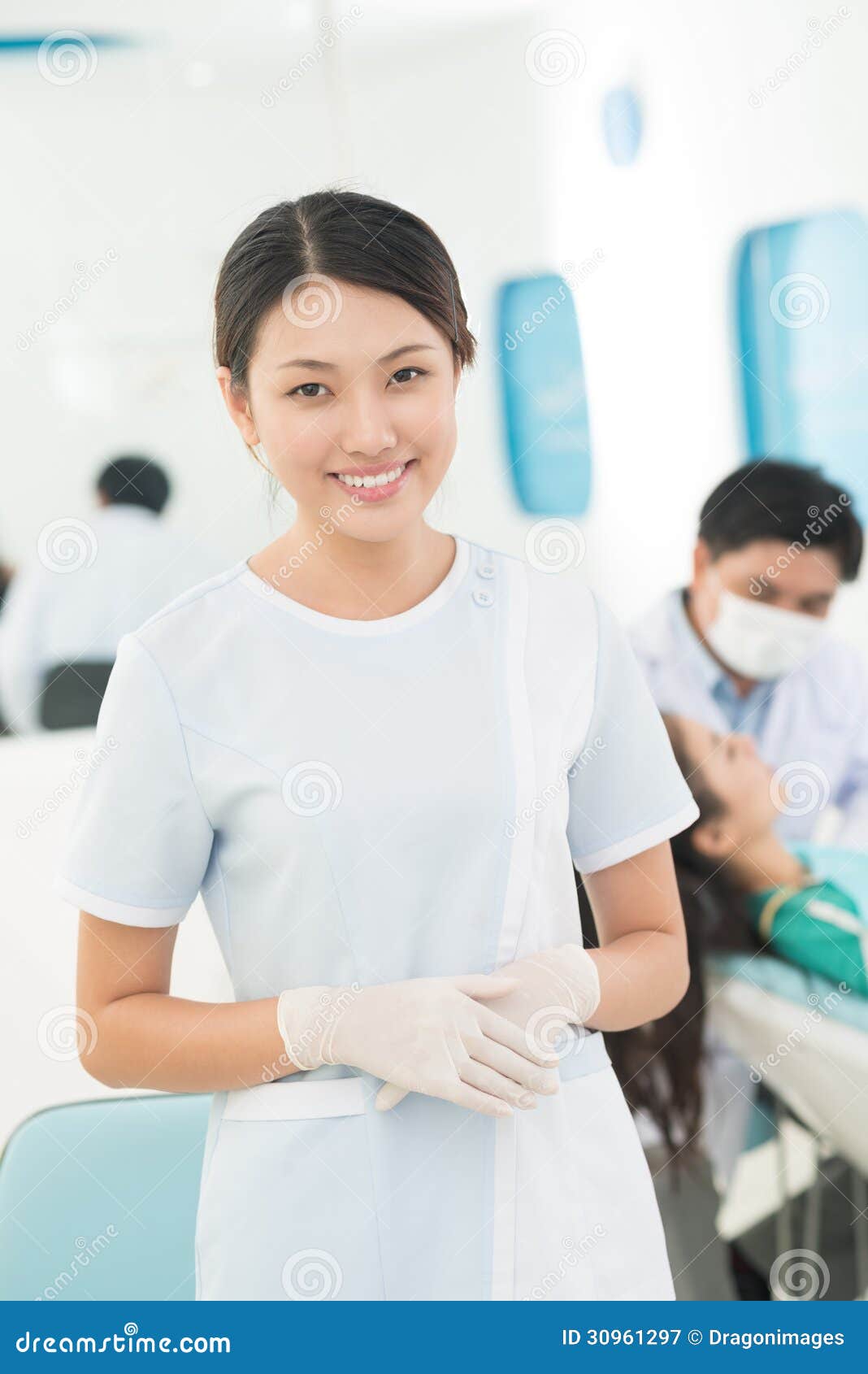 年轻工人. 协助在牙科的一名年轻医护人员的垂直的画象