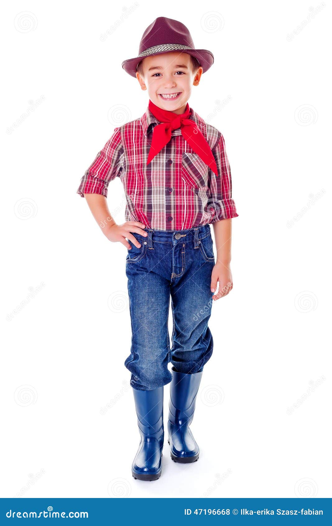 蓝色牛仔裤、靴子和帽子的愉快的偶然农业学家男孩