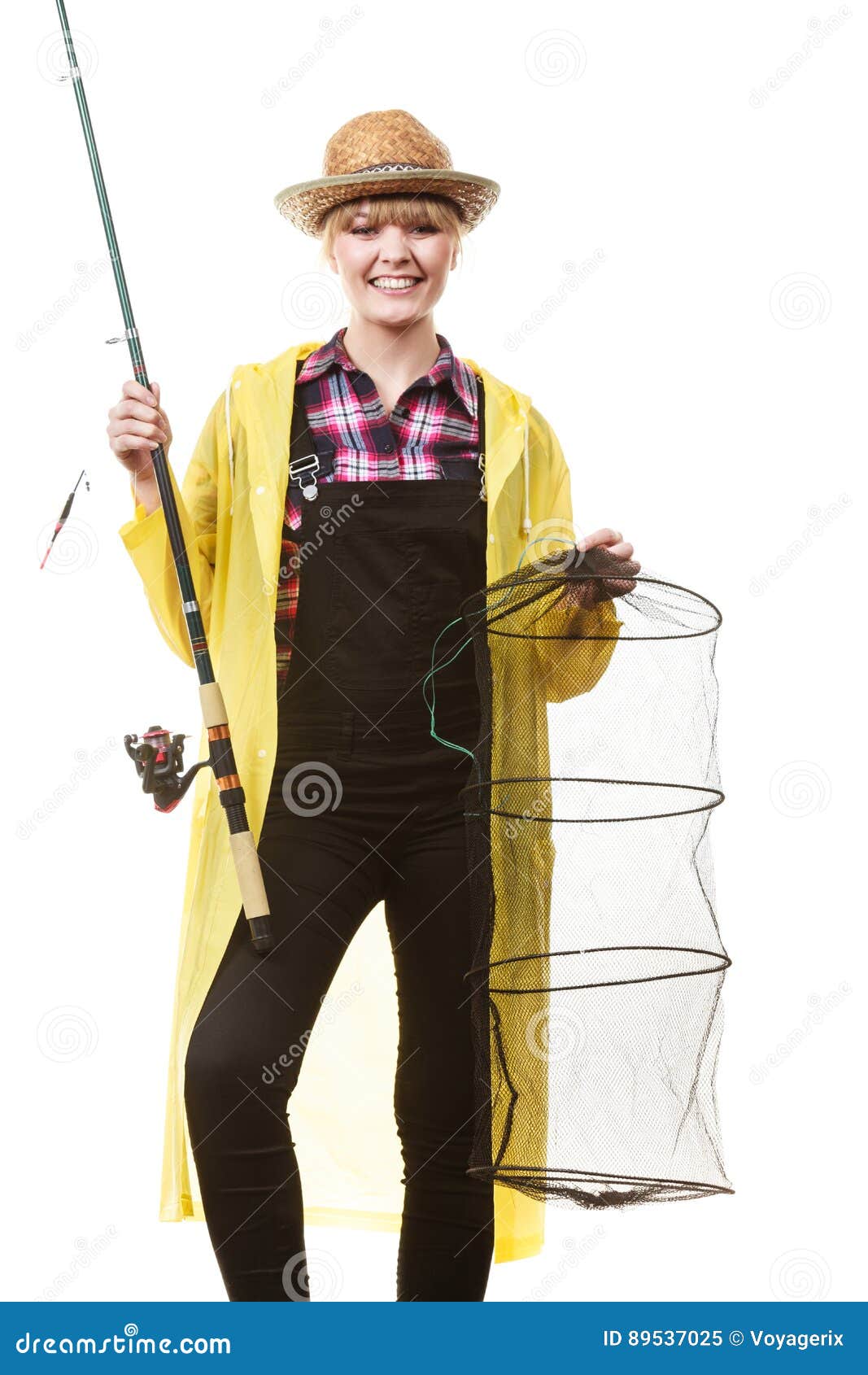 拿着钓鱼竿和keepnet的愉快的妇女. 转动，渔，快乐的女渔翁概念 拿着钓鱼竿的黄色雨衣的愉快的获得妇女和的keepnet乐趣