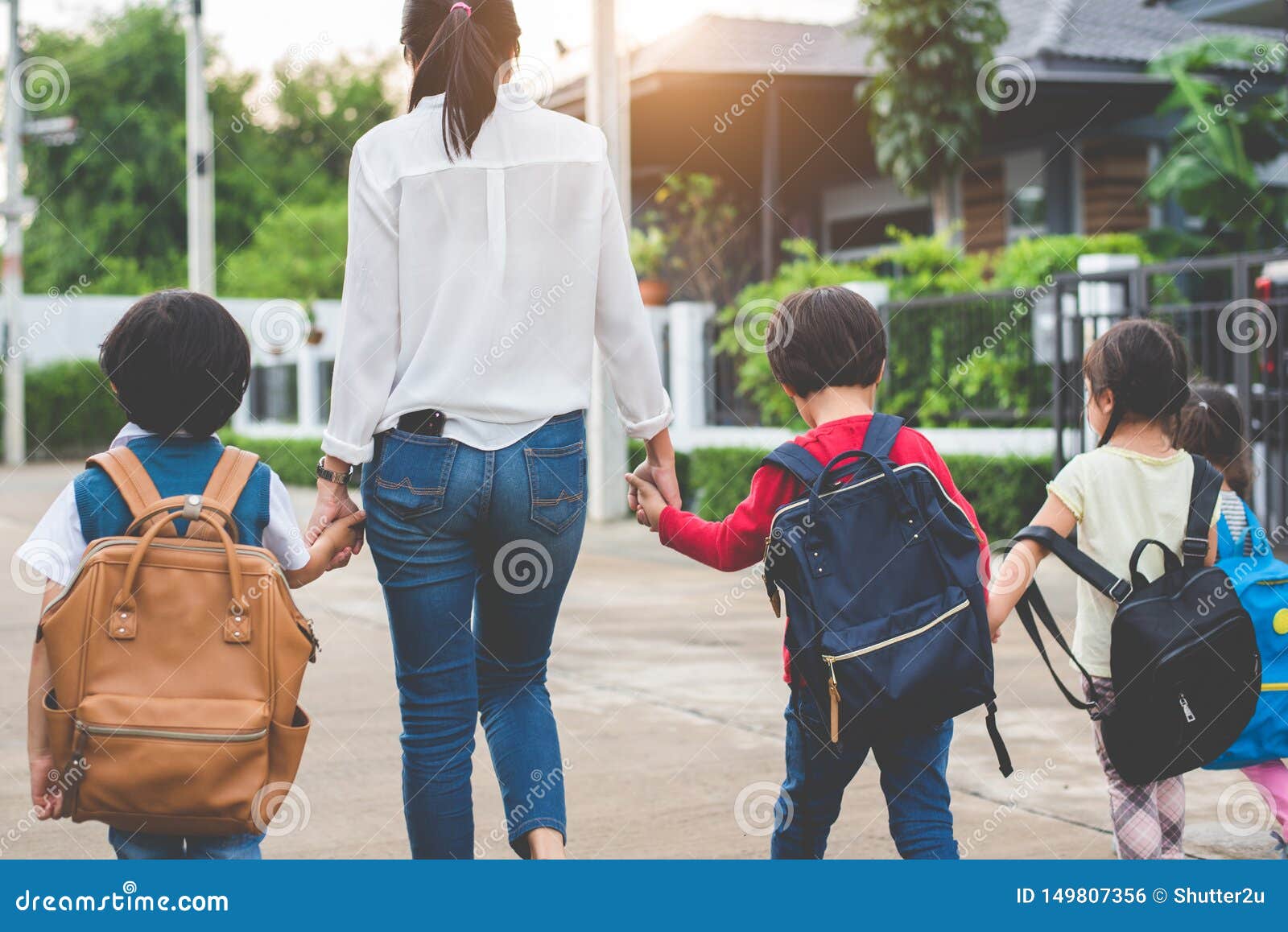 握手的小组母亲和孩子去教育与书包 妈妈带来孩子走到学校乘车与一起. 握手的小组母亲和孩子去教育与书包 妈妈给学校乘车带来孩子走与书包一起 回到学校和教育幼儿园 父母儿子姐妹家庭