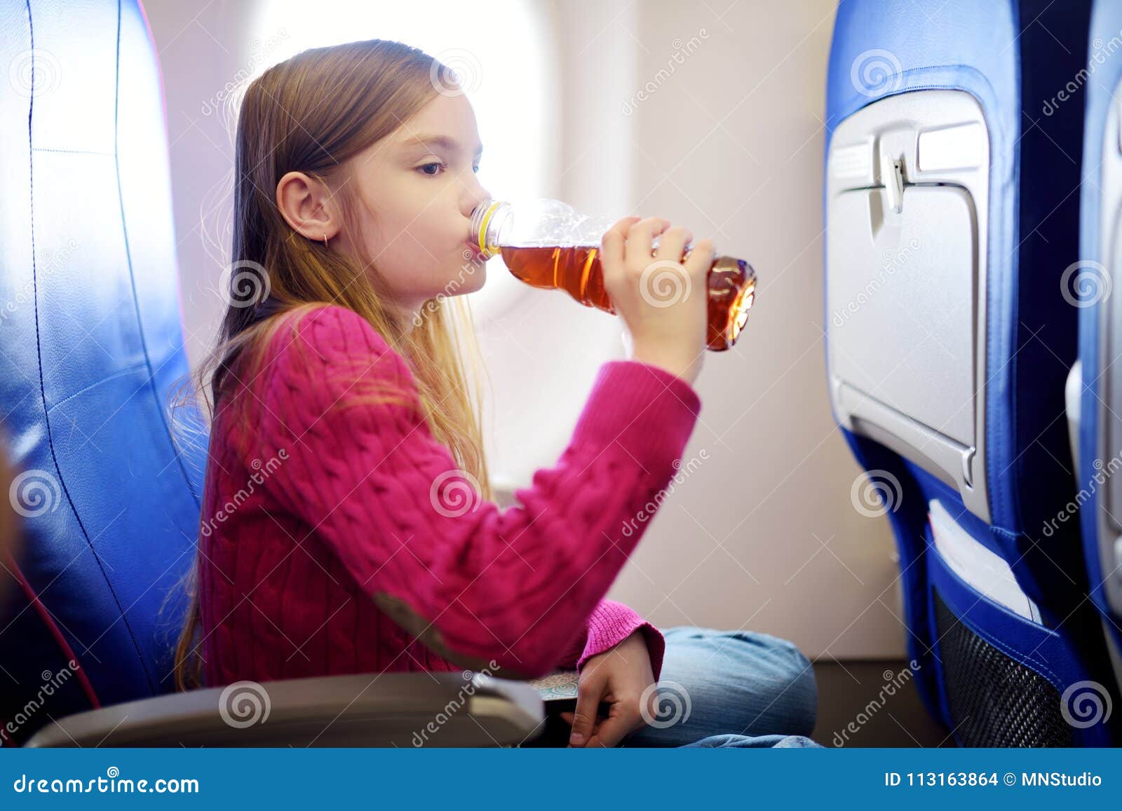 旅行乘飞机的可爱的小女孩 坐由航空器窗口和喝饮料的孩子 旅行与孩子海外